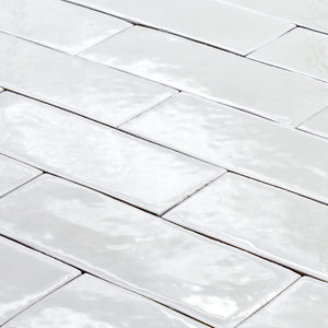 angled view of a group of popcorn cloud white 2x6 glossy subway tiles with a soft texture and uneven edges in a brick layout. 