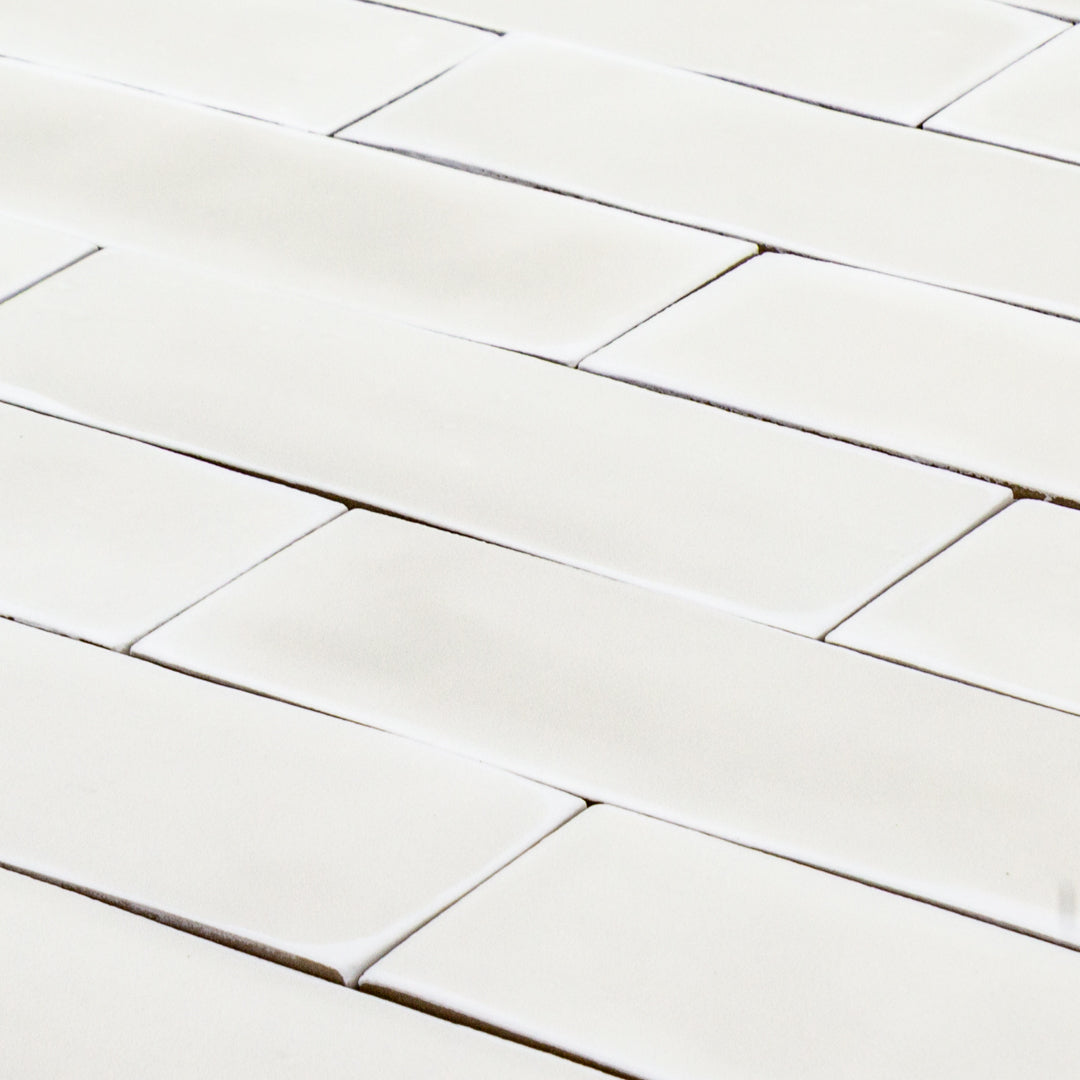 angled detailed view of a group of popcorn cloud white 2x6 matte subway tiles with a soft texture and uneven edges in a brick layout. 