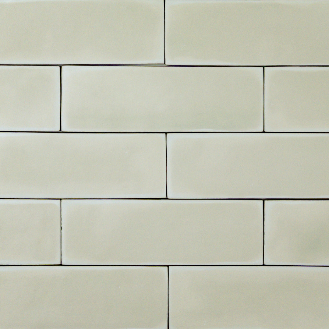 a group of light green sage2x6 matte subway tiles with a soft texture and variance in a brick layout. 