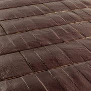 Angled close up view of 3x12 burgundy textured tiles arranged in a brick layout. 