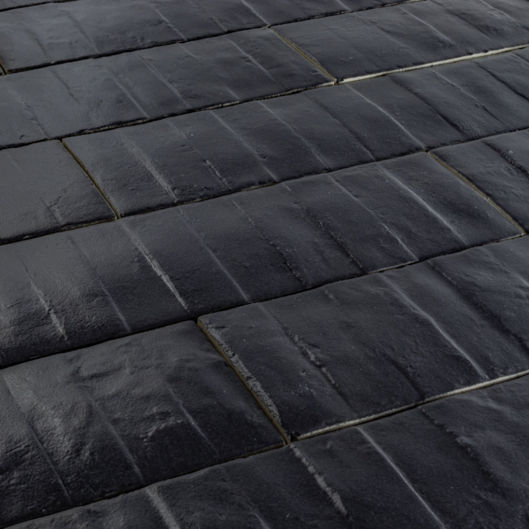 Angled close up view of 3x12 dark navy blue textured tiles arranged in a brick layout. 