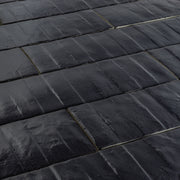 Angled close up view of 3x12 dark navy blue textured tiles arranged in a brick layout. 