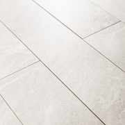 Angled close up view of a group of 4x24 snow white stone look tiles in a brick layout. 