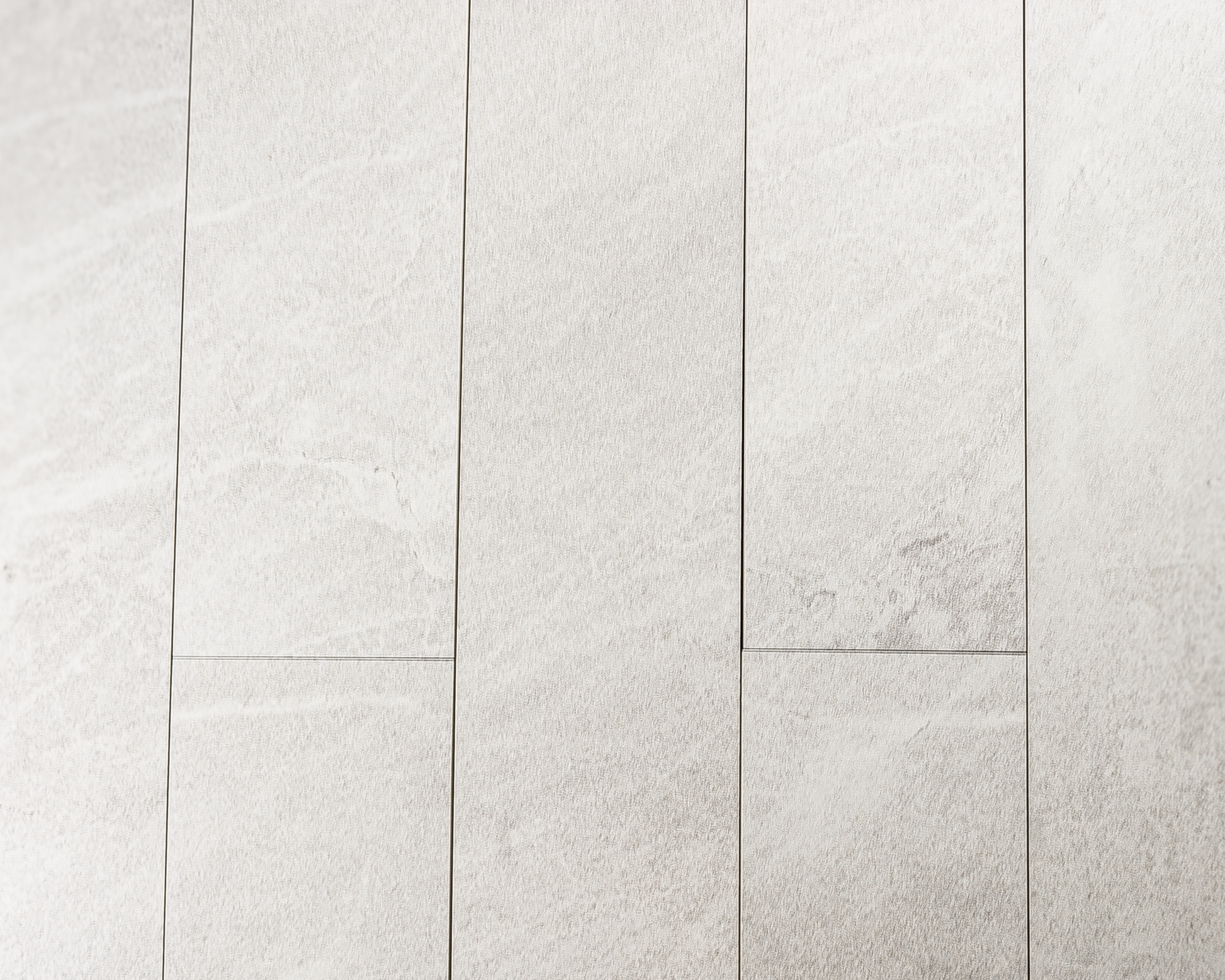 Ariel close up view of a group of 4x24 snow white stone look tiles in a brick layout. 