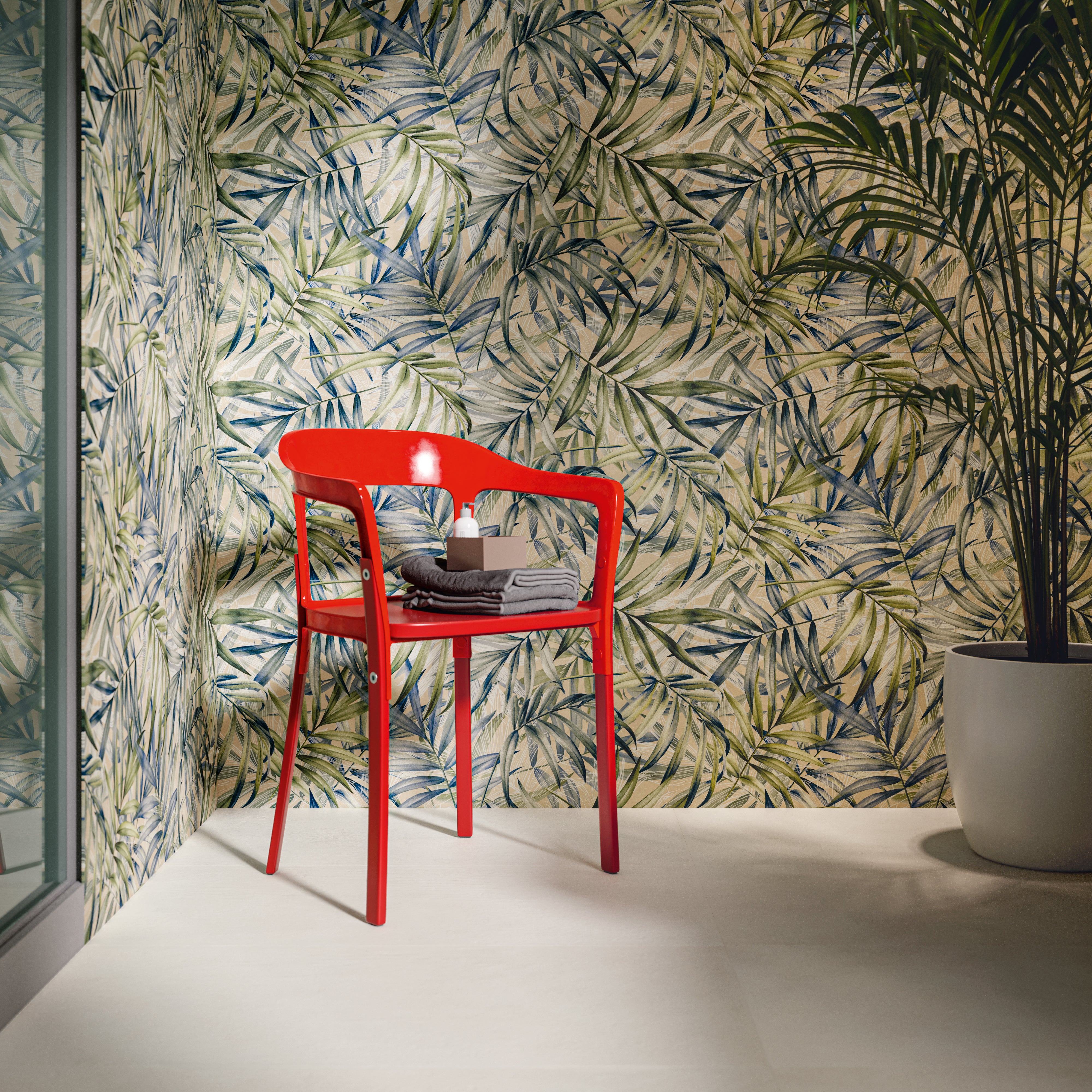 A bathroom corner with a bold red chair and the backdrop is our jardin palm leaf pattern tiles with green and white. 