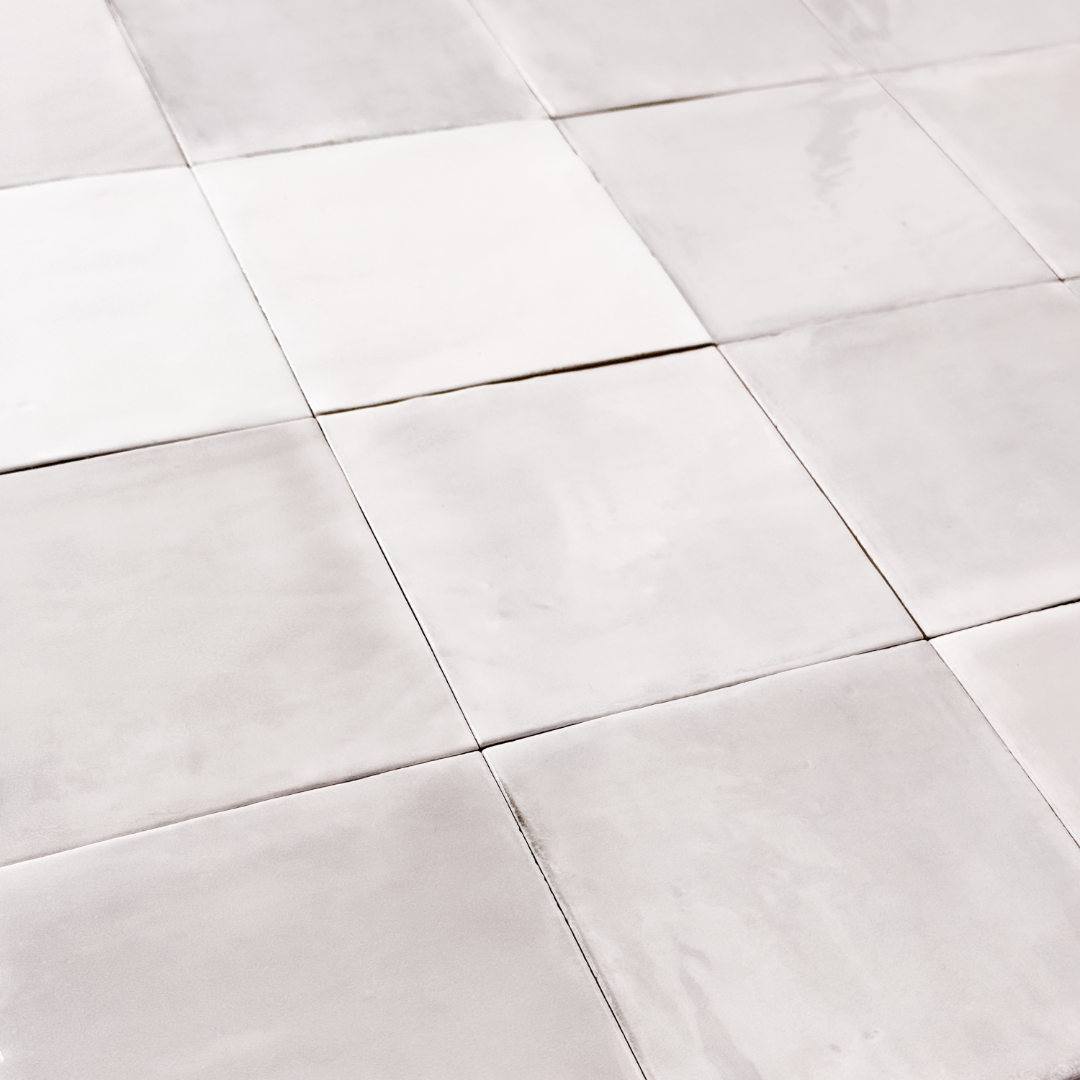 Angled ariel view of a group of glossy 5x5 textured light grey zellige tiles showing the textured edges and colour variation. 