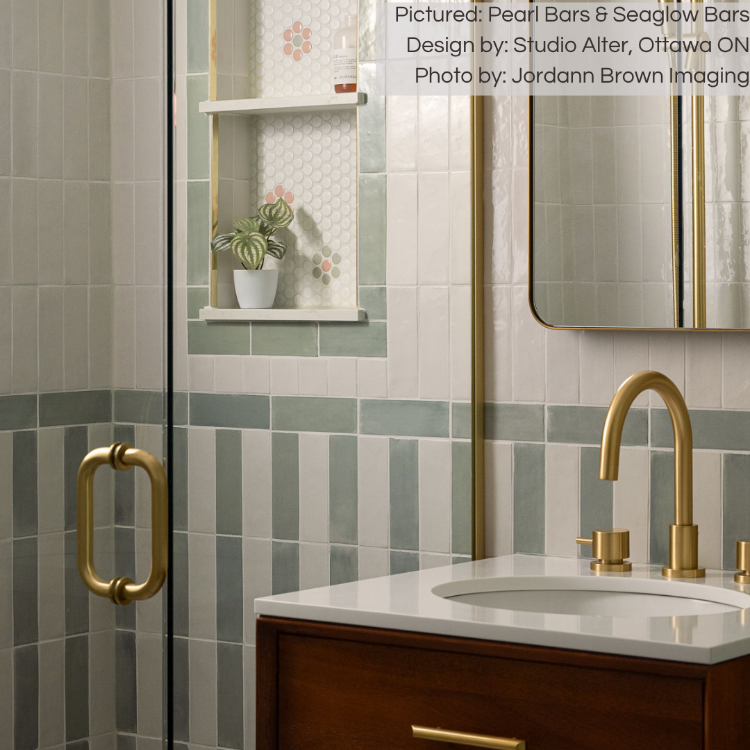 A bathroom wall and shower tile installation with gold accents. The tiles are seaglow coastal green and pearl white in a pattern stripe layout. 