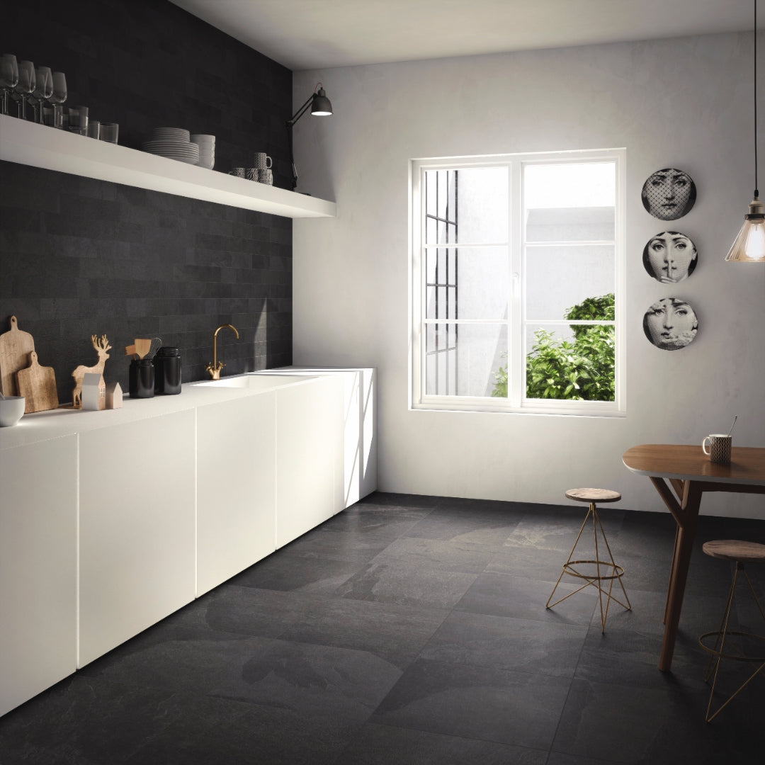 A modern kitchen installation of black slate look tiles on the floor and backsplash. There is a subtle colour variance and pattern. The painted walls, cabinets and open shelves are white to give a high contrast monochromatic look. 