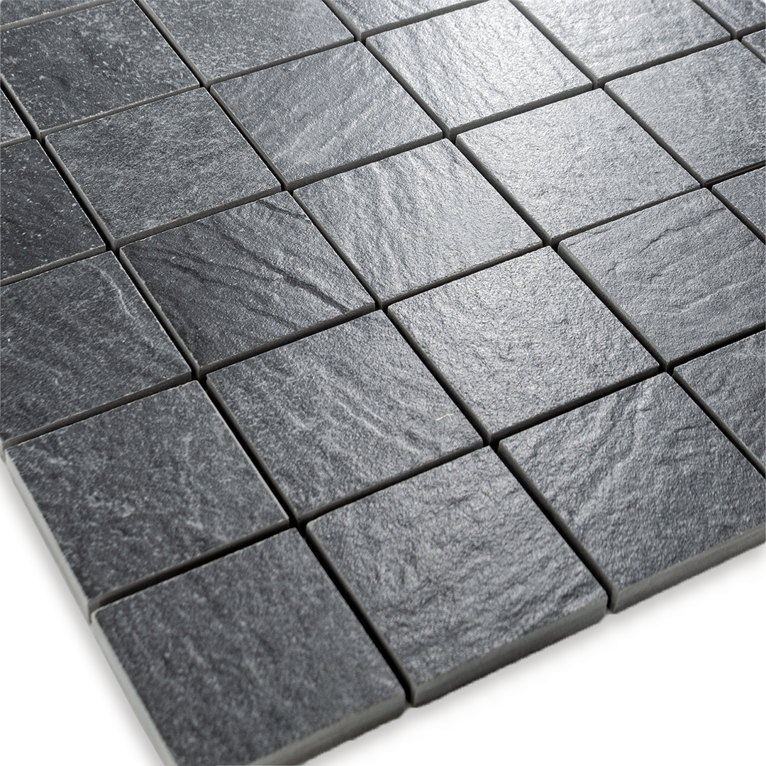 Angled close up view of a 2 inch square 12x12 sheet mosaic in a slate look black stone to highlight the texture and pattern. 