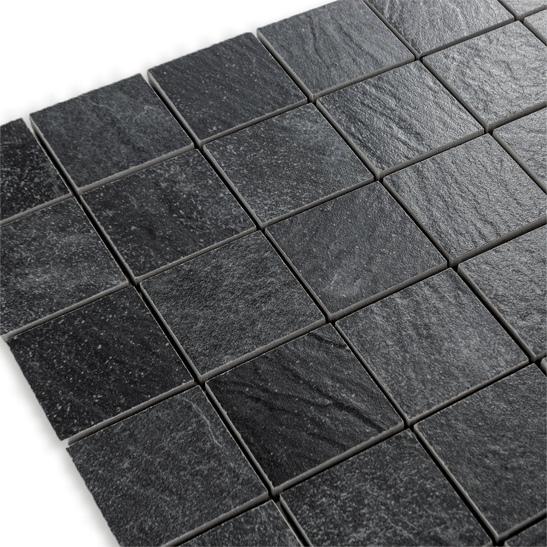 Angled close up view of a 2 inch square 12x12 sheet mosaic in a slate look black stone. 