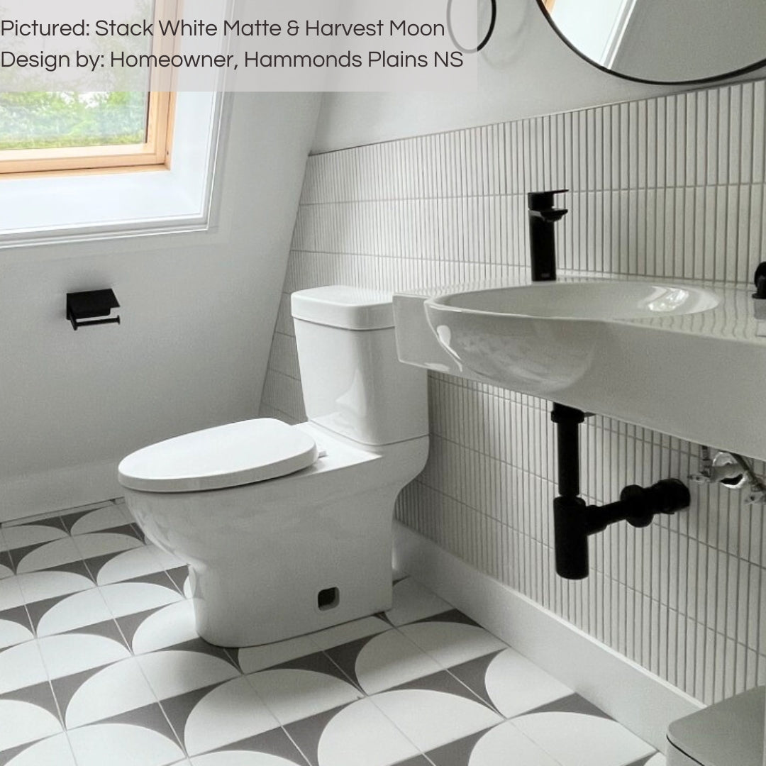 A bright white washroom featuring white plumbing fixtures, harvest moon semicircle pattern tiles and a tiled backplash. the tiles on the backsplash are white matte kitkat mosaics stacked vertically on the lower half of the wall. 