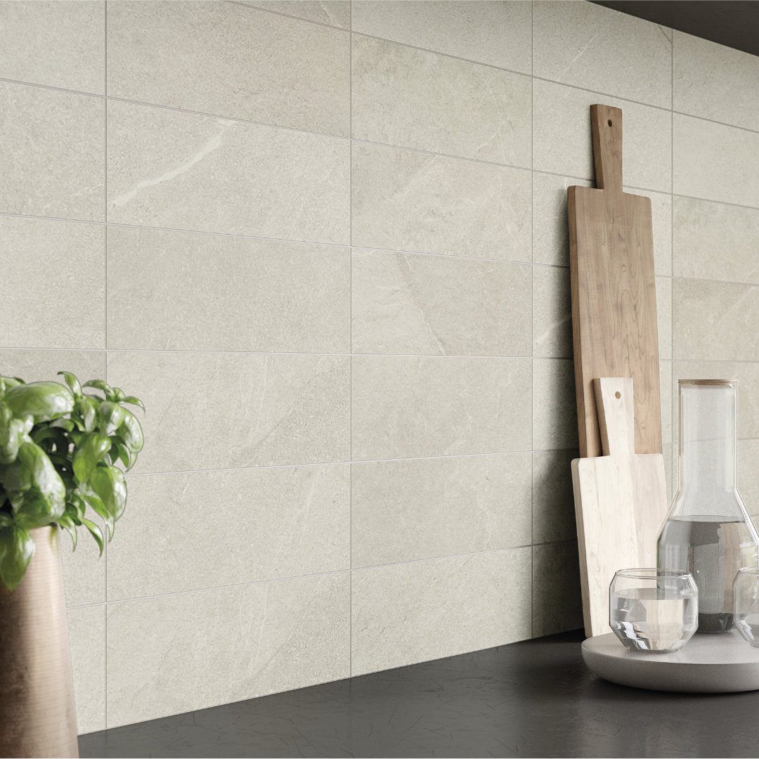 A modern charcoal kitchen with light wood accents, and dark counter tops. the stonehaven light stone look tile with very fine pattern and colour variance is in 4x12 on the backsplash. 