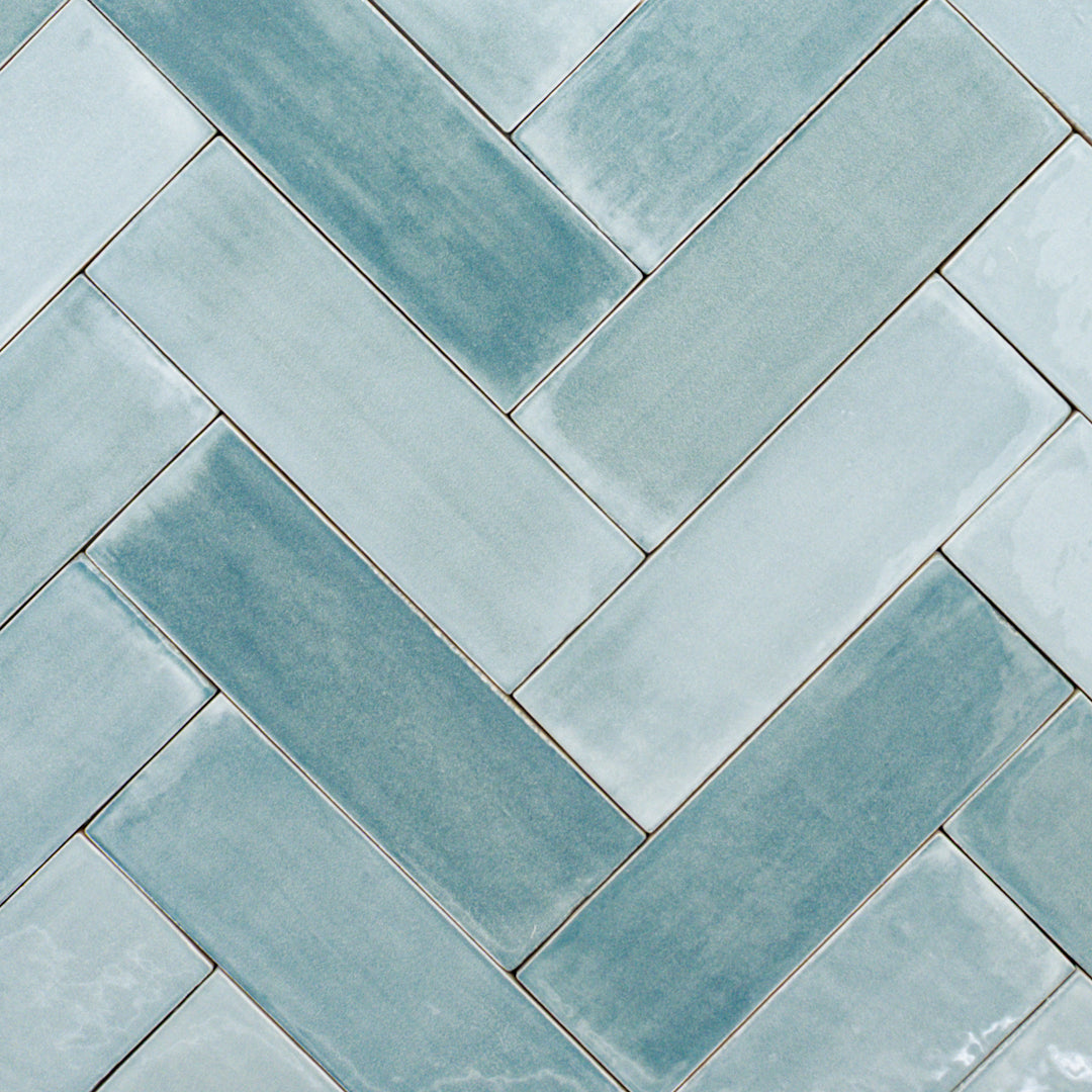 a group of 2x6.5 glossy aqua azure blue subway tiles with colour variation in a herringbone layout