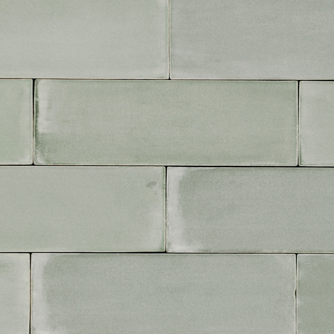 A brick tile flat lay featuring 2x6.5 seaglow bars; a glossy light coastal blue and aquamarine green tile with heavy colour variation. 