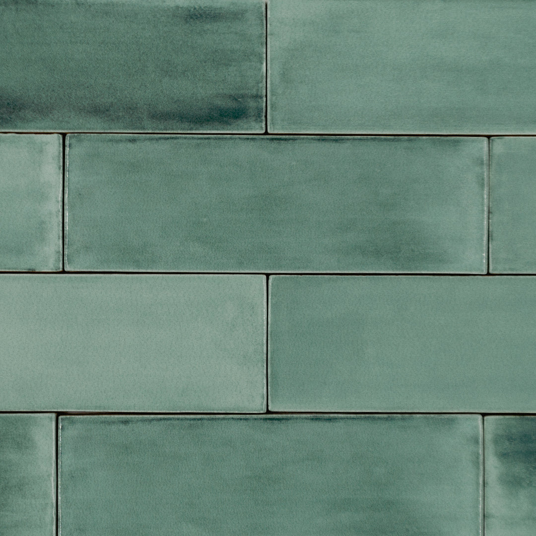 Ariel view of a brick tile flat lay featuring brushed green bars; a 2x6.5 glossy cool dark earthy eucalyptus green tile