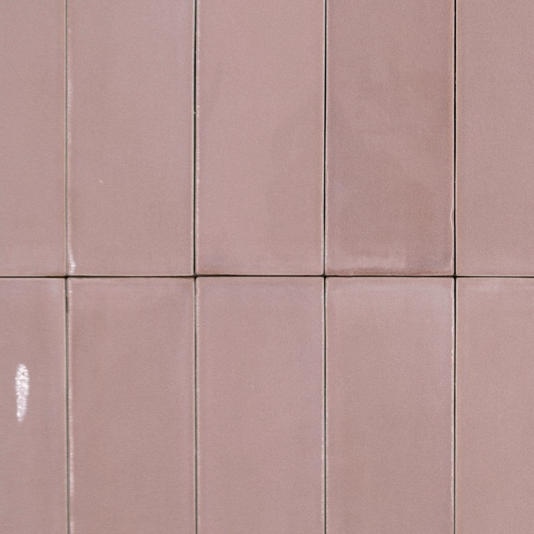 A stacked grouping of subway tiles in a flat lay. the tiles are 2x6.5 glossy pink. 