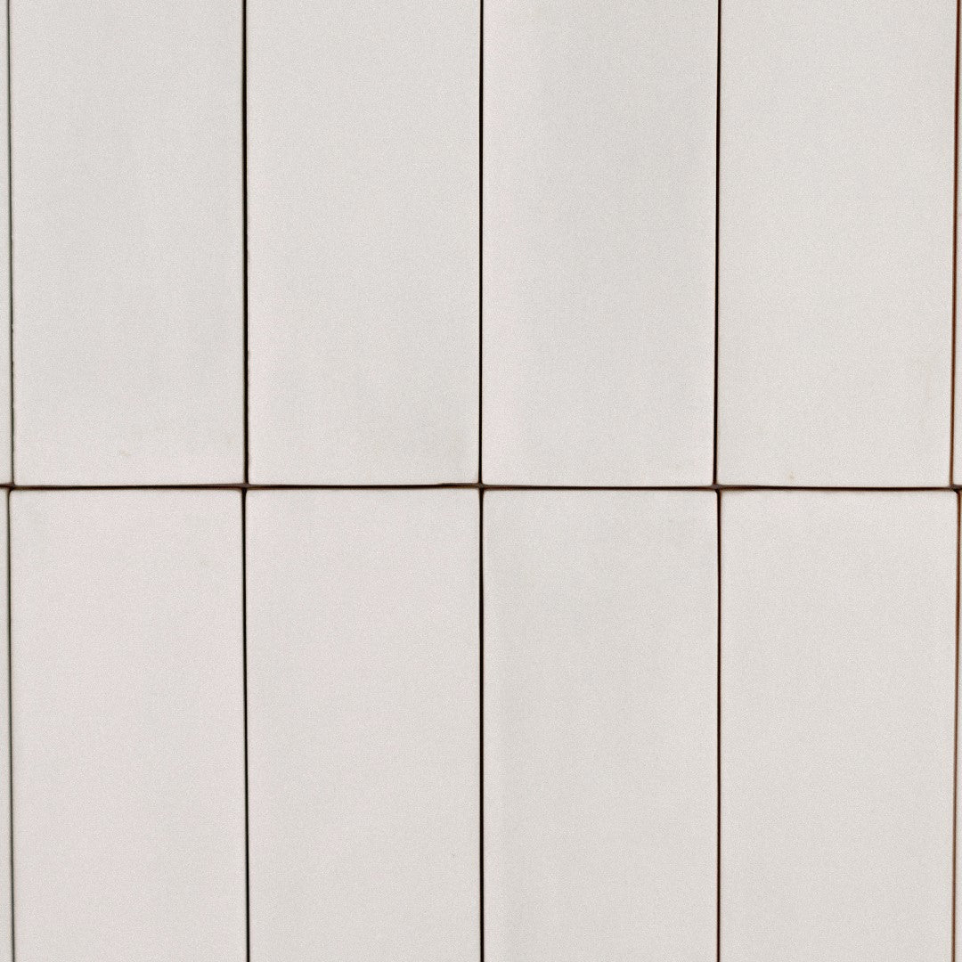 Ariel view a of a stack tile flatlay featuring 2x6.5 milkstone bars; a matte off white cream tile with heavy colour variation. 