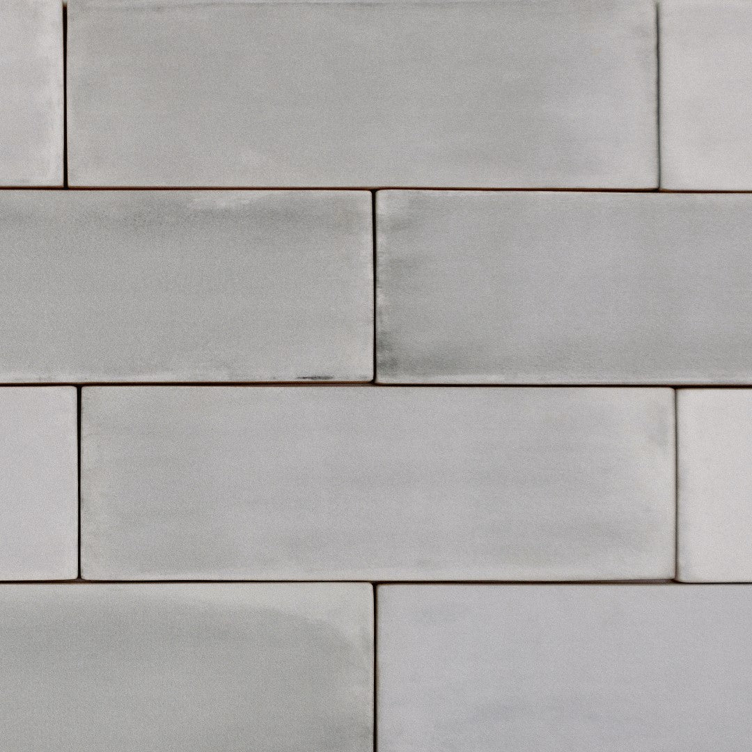 Ariel close up view of a brick tile  layout featuring 2x6.5 misty gray bars; a matte grey silver tile with heavy colour variation. 