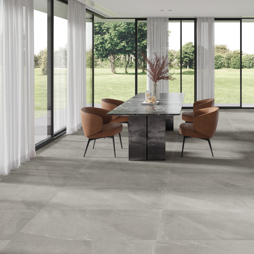 Open concept dining area with cognac leather chairs and a stone dining table. the tiled floors are a large scale limestone look in matte taupe.
