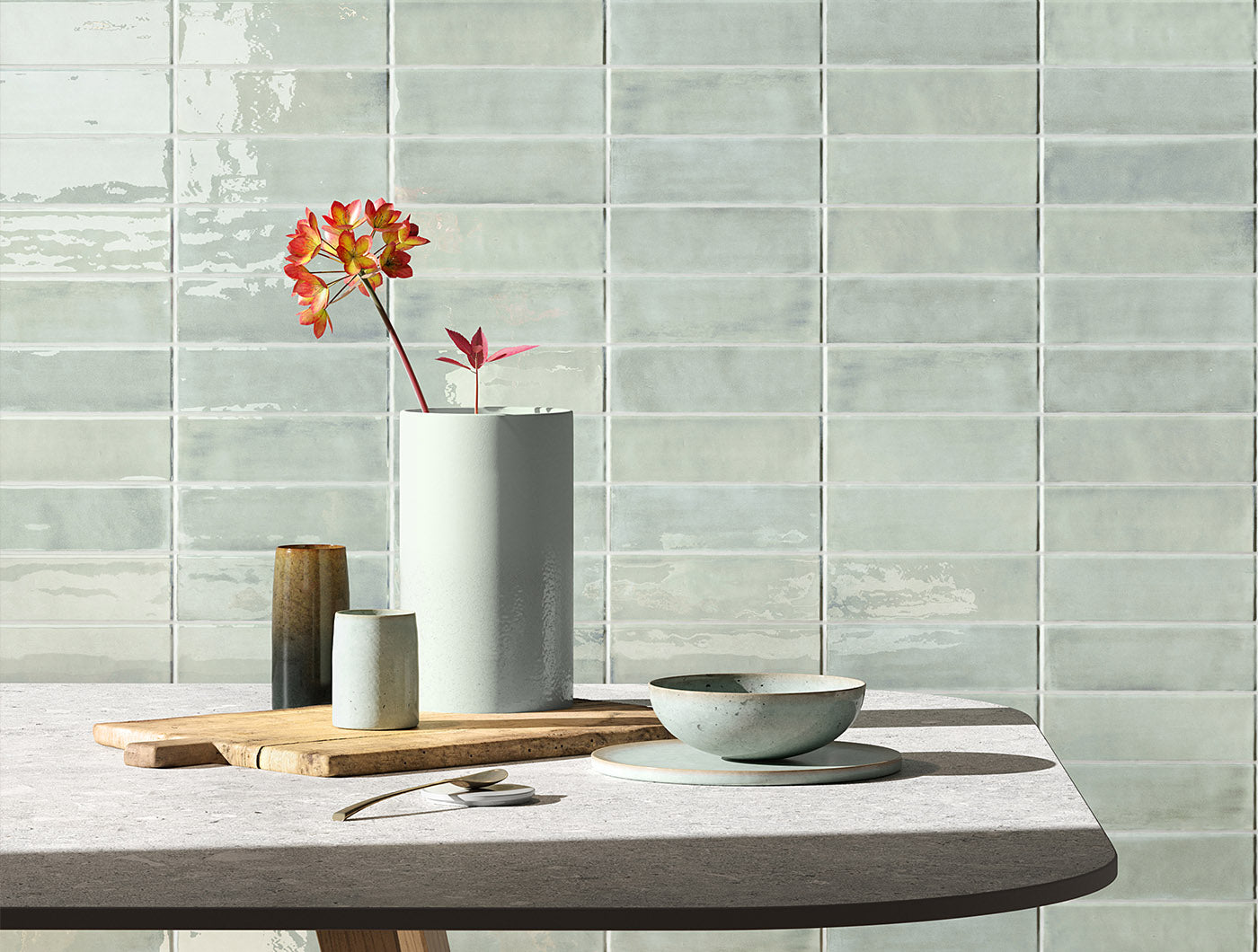 A tiled wall vignette featuring 2x6.5 seaglow bars; a glossy delicate coastal blue and aquamarine green tile with heavy colour variation. 