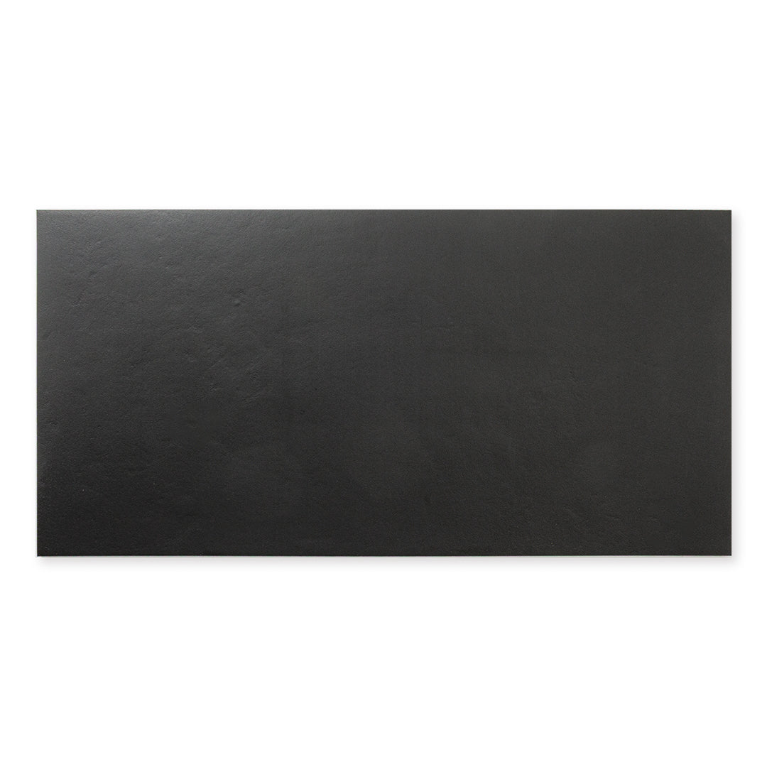 A single tile of black 12x24 tile, checkmate black features a slight stone look, with subtle texture and a matte finish. 
