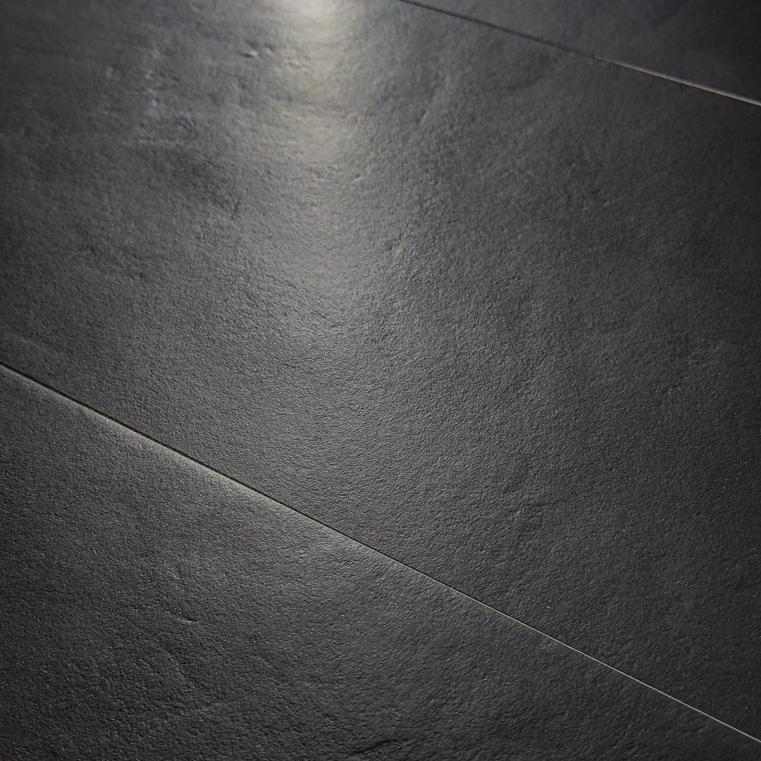 Angled close up view of black 12x24 tile, checkmate black features a slight stone look, with subtle texture and a matte finish. 
