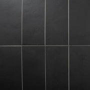 An ariel view of 8 tiles laid in a vertical stack pattern featuring black 4x12  with a soft stone appearance and texture. 