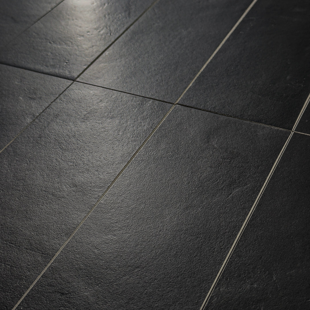 Close up photo of black 4x12 tile laid out in a vertical brick pattern with a soft stone appearance and texture. 