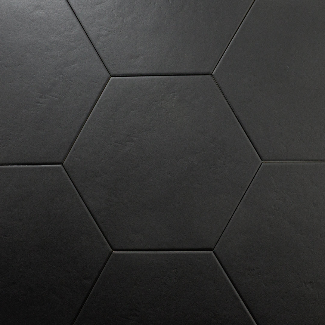 Close up view of black 9x10 hexagon tiles. There is one tile centered with 6 tiles surrounding it to form a honeycomb look. The checkmate black features a slight stone look, with subtle texture and a matte finish. 