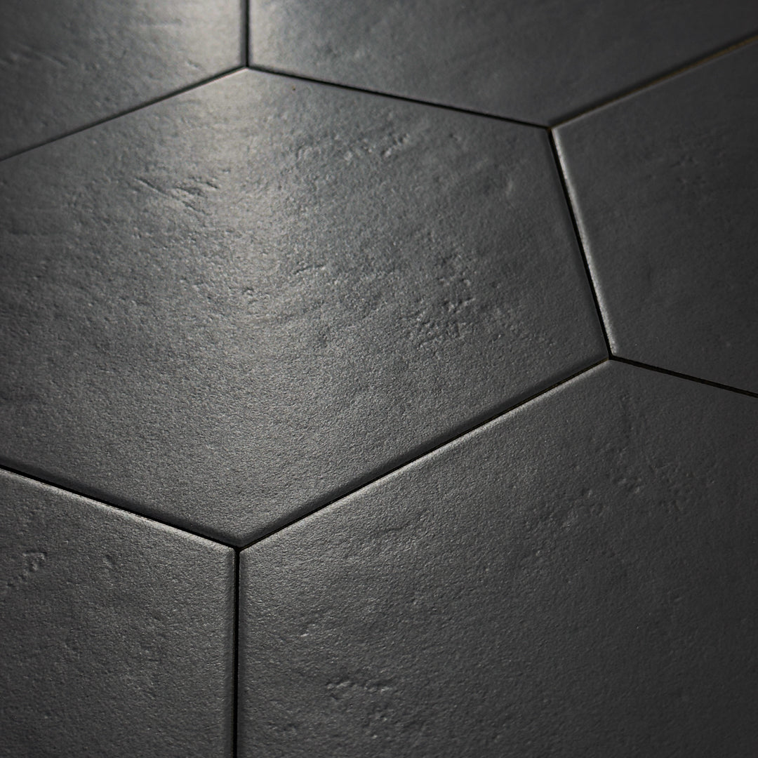 Angled close up view of black 9x10 hexagon tile, checkmate black features a slight stone look, with subtle texture and a matte finish. 