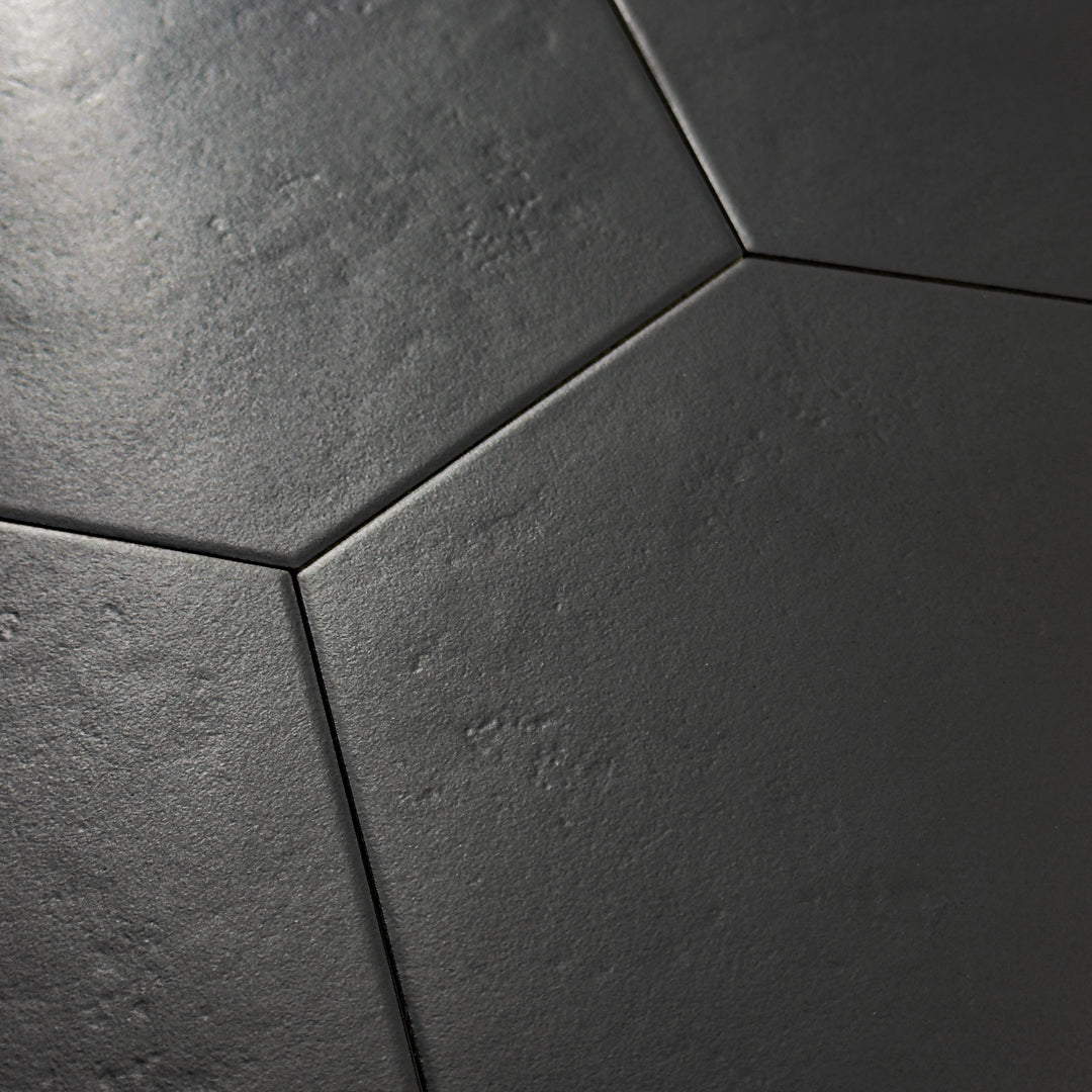 Angled close up view of black 9x10 hexagon tile, checkmate black features a slight stone look, with subtle texture and a matte finish. There are 4 tiles laid together. 