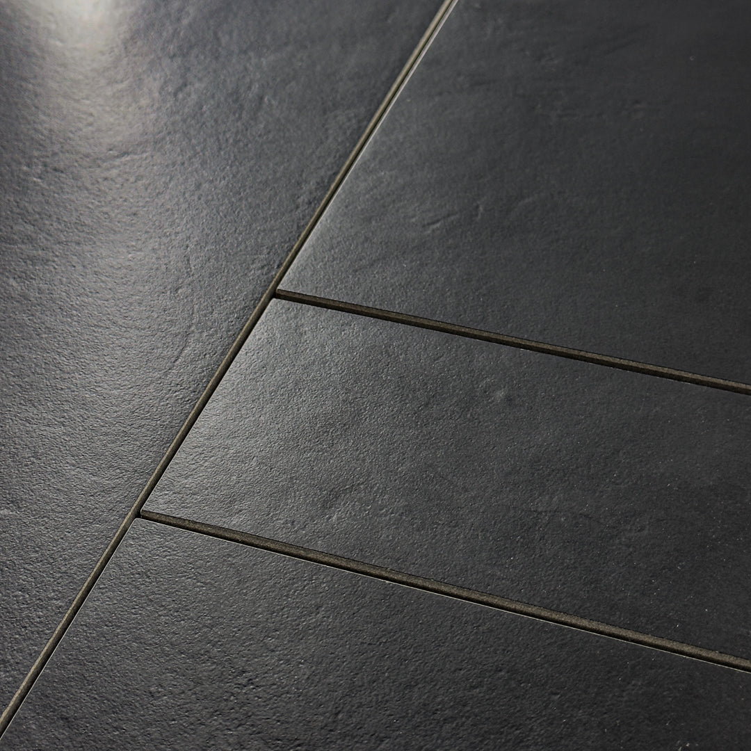 A close up view of multiple size tiles in Black Checkmate tile to highlight the soft stone appearance and texture. 