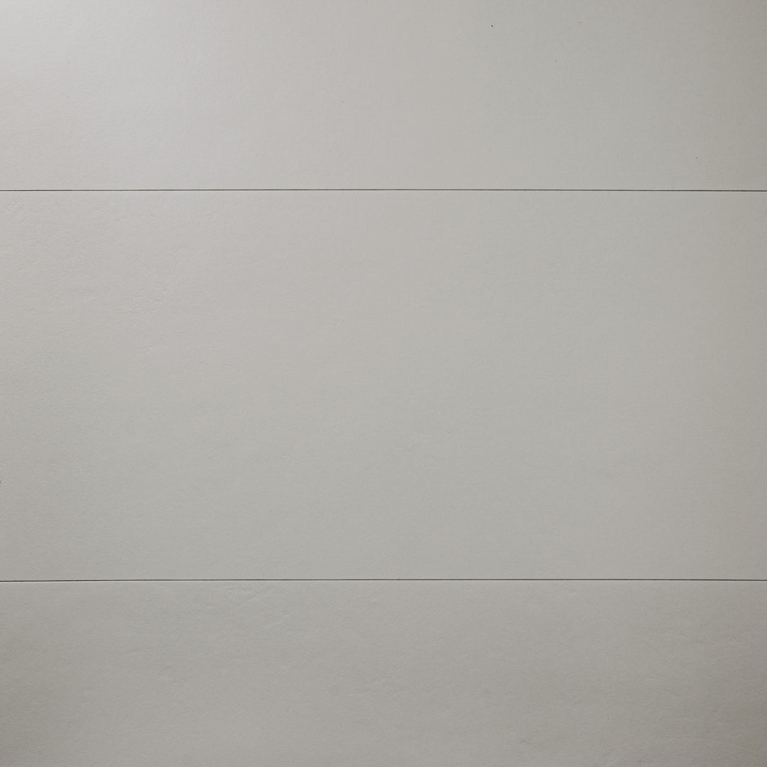A close up view of three 12x24 grey tiles with a soft stone appearance and texture. 