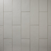 Multiple Grey 4x12 tiles laid out in a vertical brick pattern with a soft stone appearance and texture. 