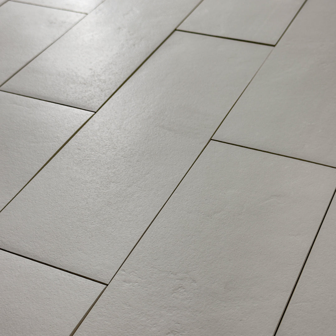 Close up photo of Grey 4x12 tile laid out in a vertical brick pattern with a soft stone appearance and texture. 