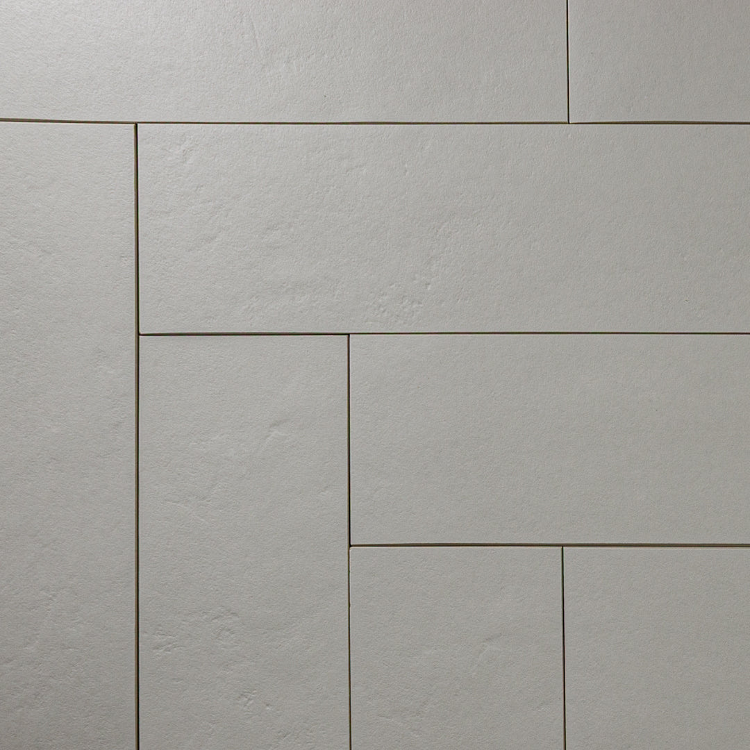 Grey 4x12 tile laid out in a herringbone pattern to highlight the corners with a soft stone appearance and texture. 
