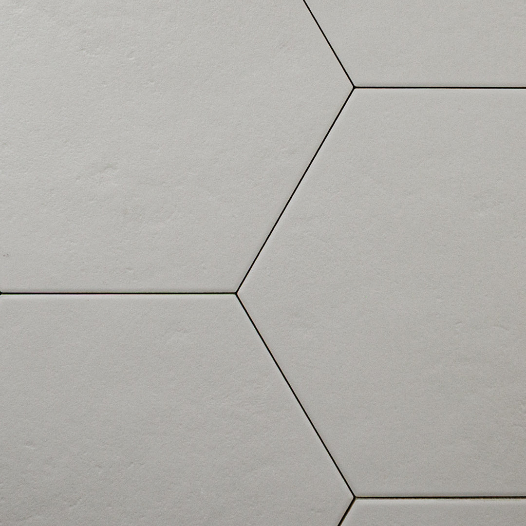 A close up ariel view of 4 9x10 hexagon tiles that are grey with a subtle texture and matte finish.