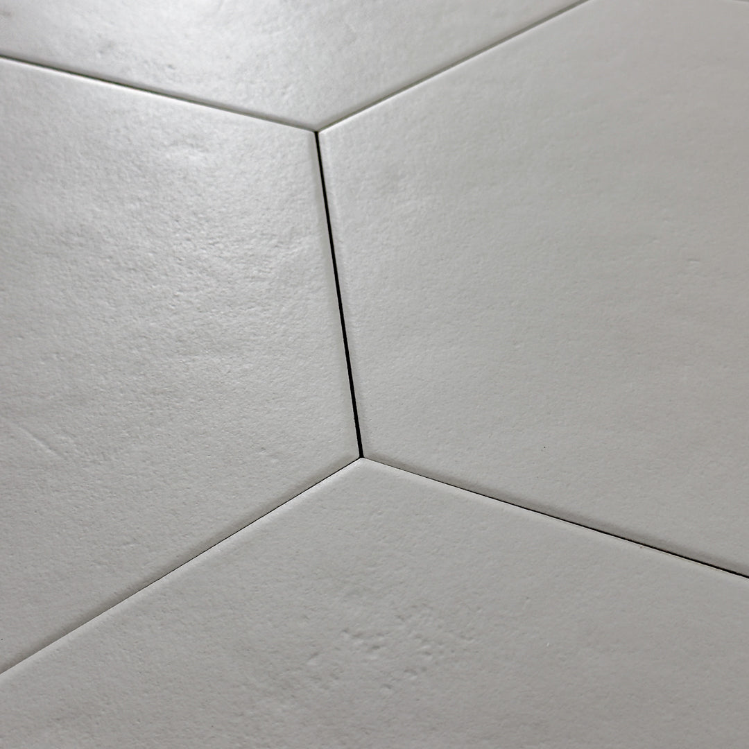 A close up view of 4 9x10 hexagon tiles that are grey with a subtle texture and matte finish.