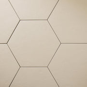A close up ariel view of 4 9x10 hexagon tiles that are beige with a subtle texture and matte finish.