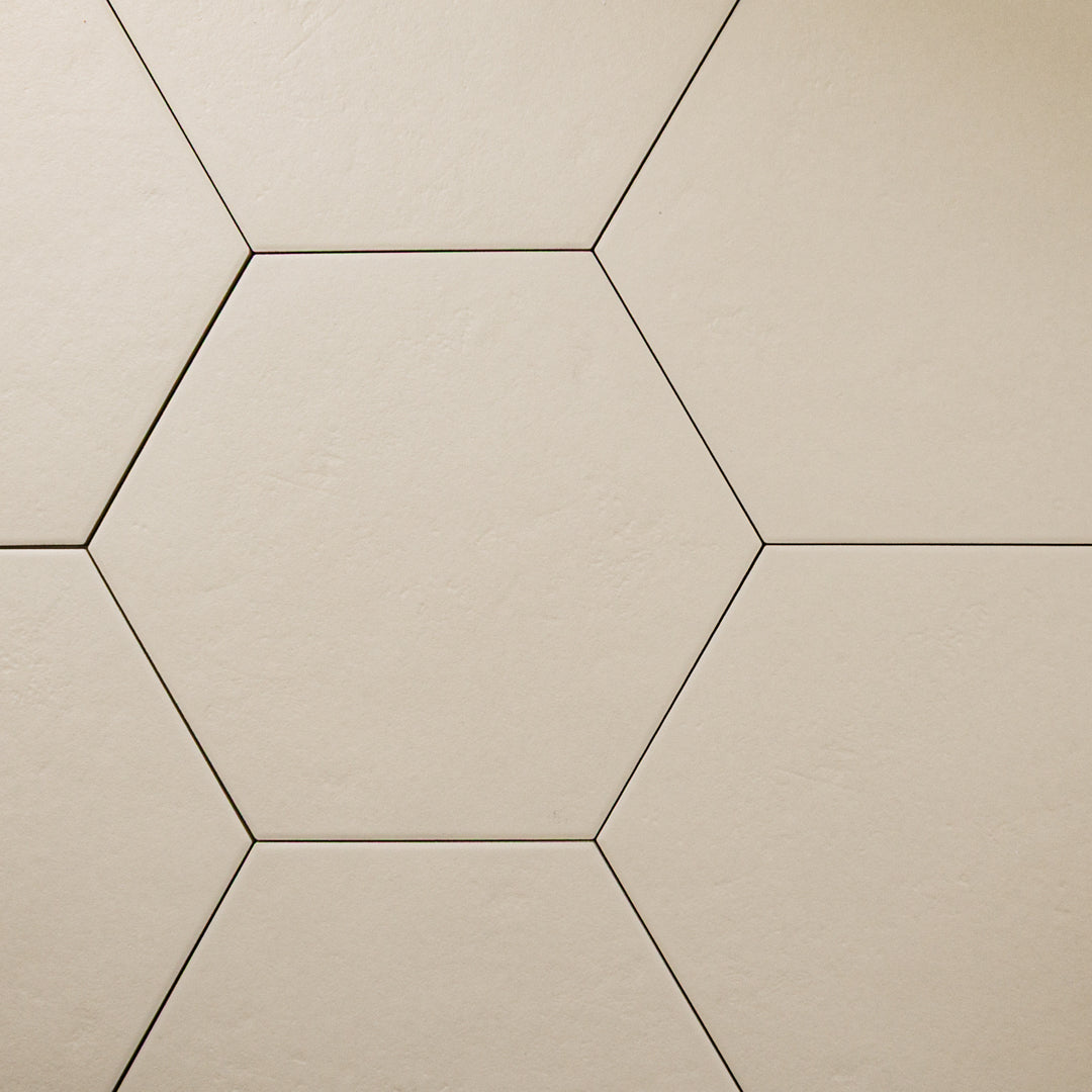 A close up ariel view of 4 9x10 hexagon tiles that are beige with a subtle texture and matte finish.