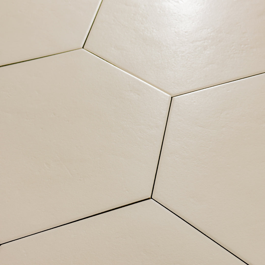A close up view of 4 9x10 hexagon tiles that are beige with a subtle texture and matte finish.
