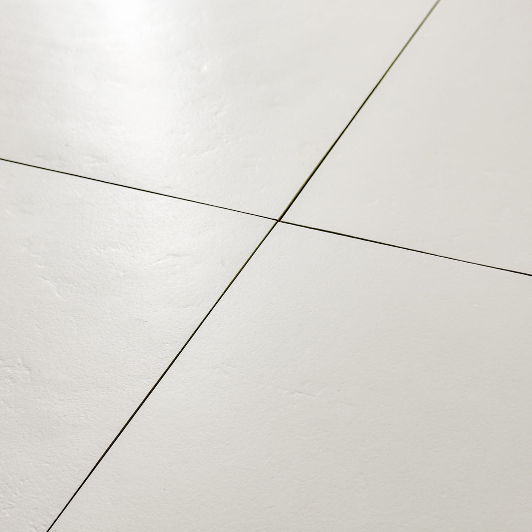 A close up view of four 12x12 white tiles highlighting the soft stone appearance and texture. 