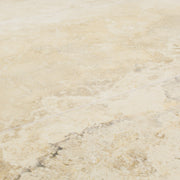 Angled close up view of two large rectangular tile that resembles travertine stone in light warm beige. 