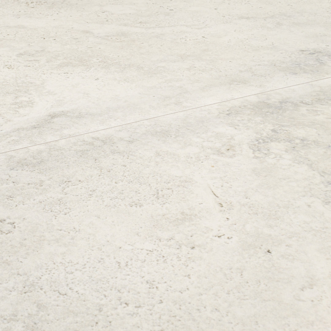 Angled close up of two large rectangular 24x48 tile that resembles travertine stone in light grey white. 