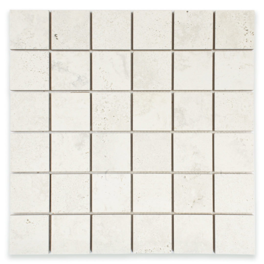 Ariel close up of a 2x2 square mosaic tile that resembles travertine stone in light grey white. 