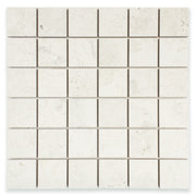 Ariel close up of a 2x2 square mosaic tile that resembles travertine stone in light grey white. 