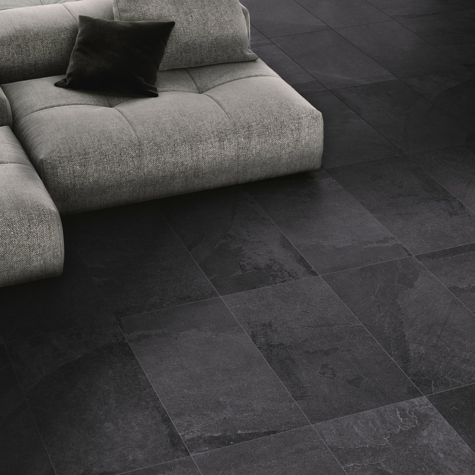 A close up of a tile floor installation in a family room. The tiles are a slate look in black matte with a subtle texture and pattern. 