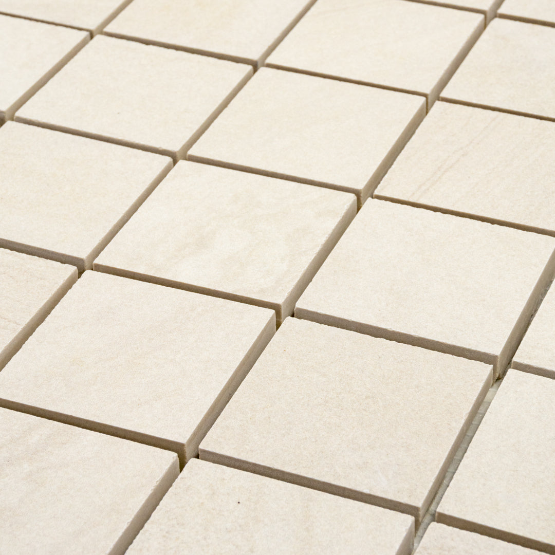 angled close up of a stone look 2x2 square mosaic in beige perfect for a shower floor, or niche accent. 