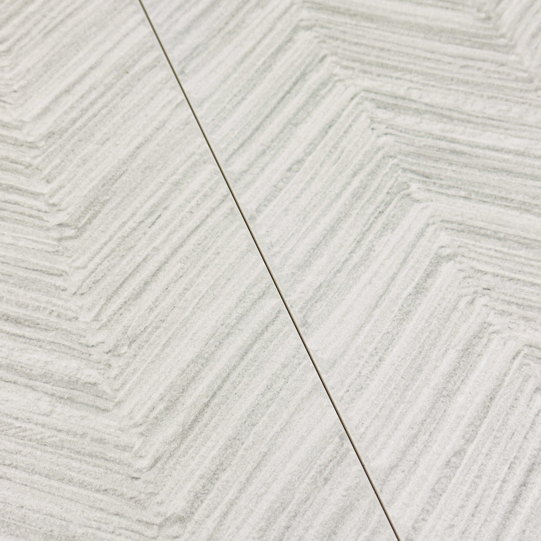 Two side by side gray solenne chevron structured stone look rectangle large tiles. 