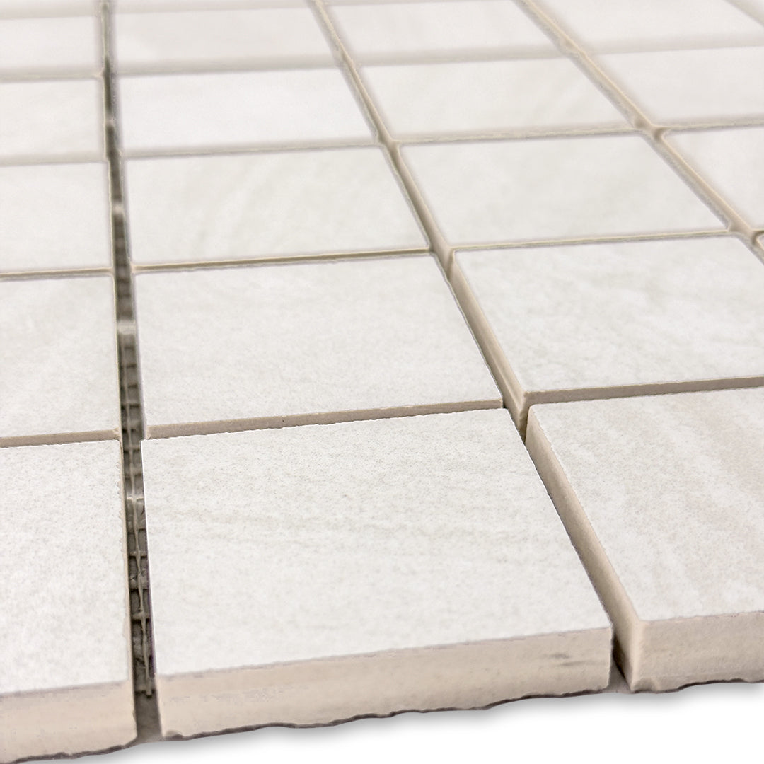 angled close up of a stone look 2x2 square mosaic in white perfect for a shower floor, or niche accent. 